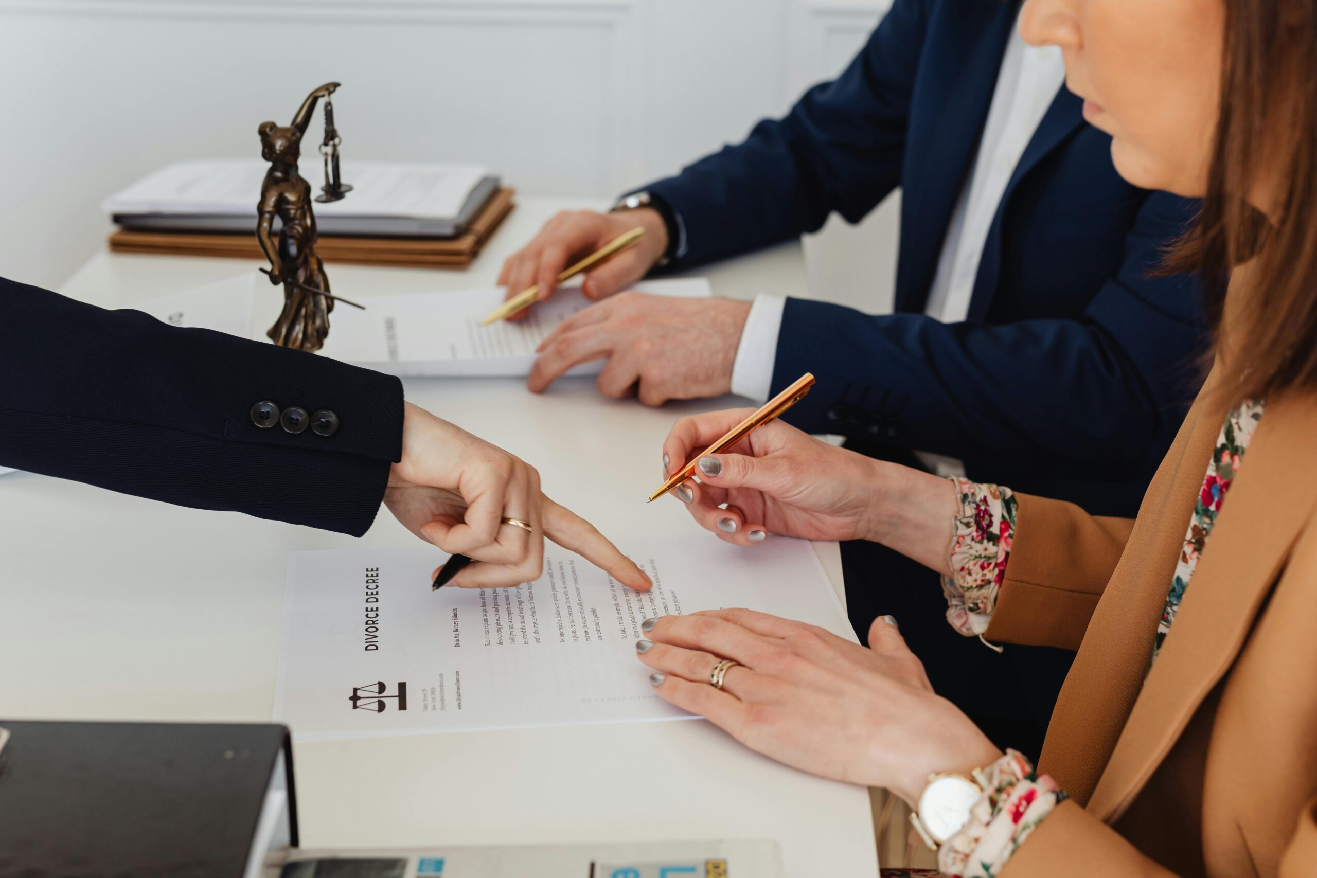 Home Hands signing a divorce decree, with a justice statue nearby, symbolizing legal proceedings.
